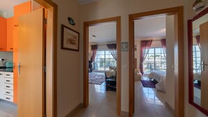 A hotel room with a bed, a desk, and a window with curtains. There is a hallway with a door leading to another room. - Lily Fabulous 1 BED APT With Roof Terrace Pool (Lagoa)