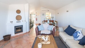 Amplia sala de estar con chimenea, un sofá y una mesa de comedor al fondo.