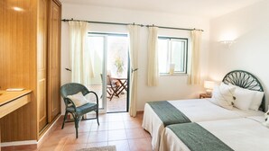 Un dormitorio con cama, escritorio, silla y vistas al exterior.