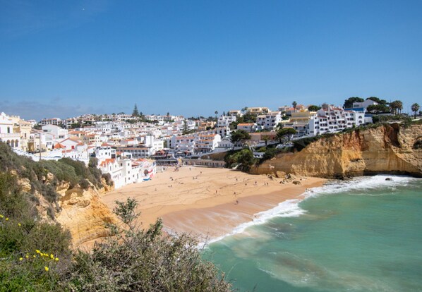 A coastal town with white buildings, a sandy beach, and a rocky cliff. - Beach House Apartment (Lagoa)