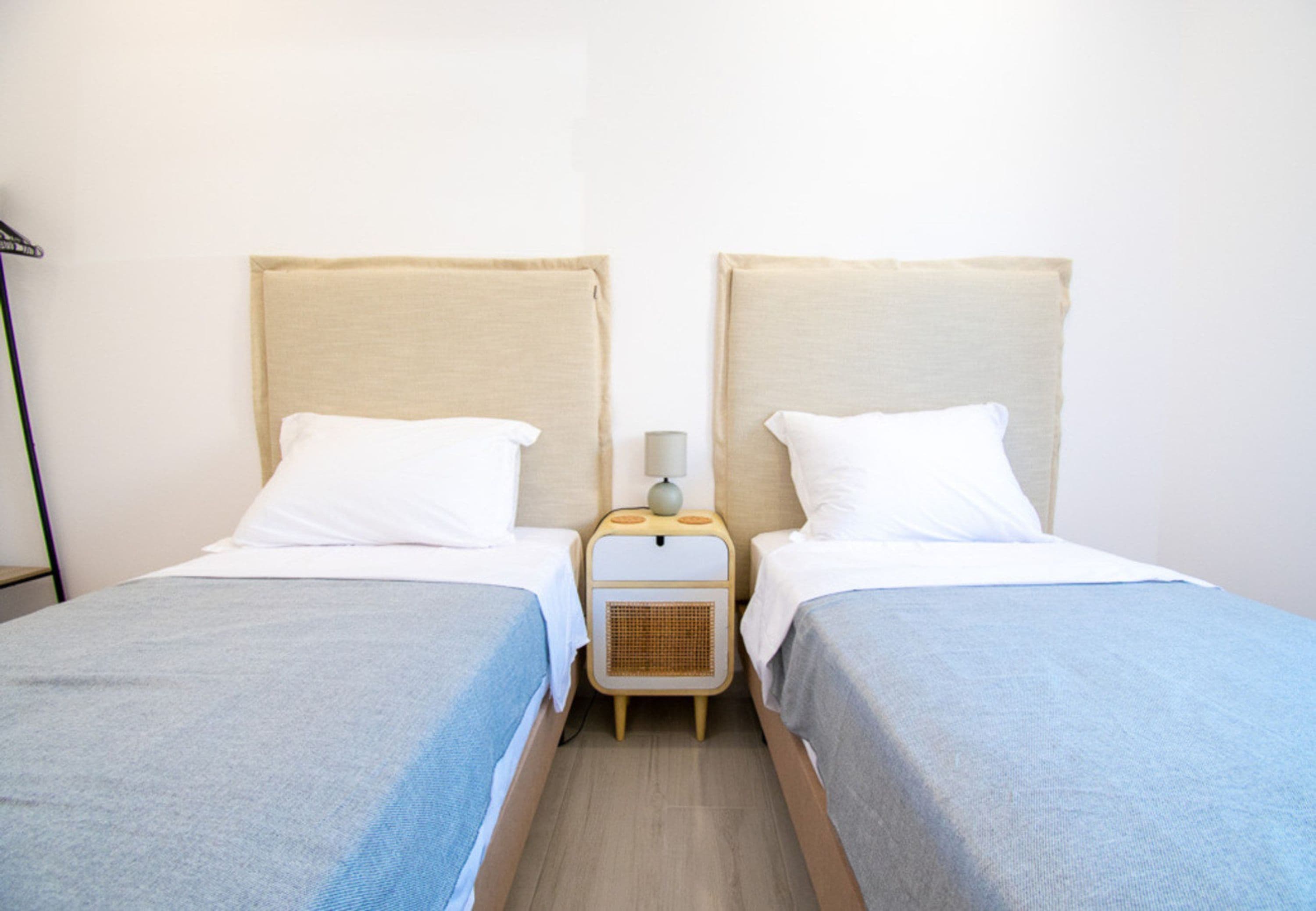 A double room with two beds, each with a headboard, a bedside table with a lamp, and a small heater.