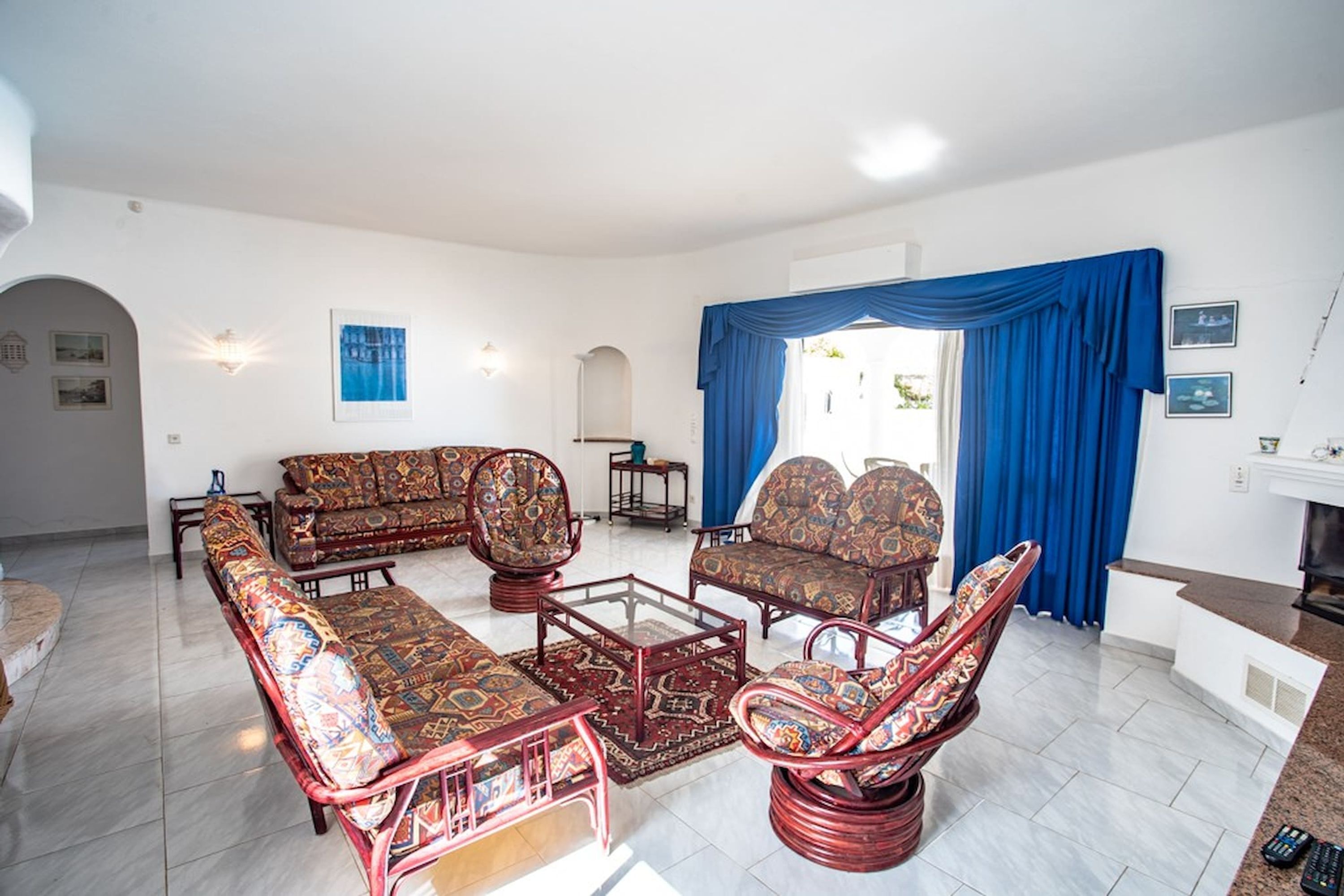 Ein Wohnzimmer mit gemusterten Sofas, einem Couchtisch und einem Essbereich mit Tisch und Stühlen.