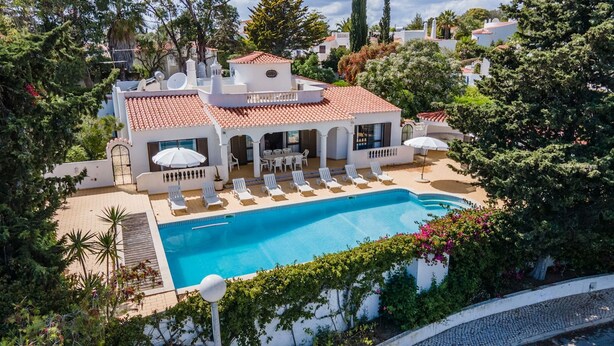 Un área junto a la piscina con piscina, sillas de descanso y sombrillas.