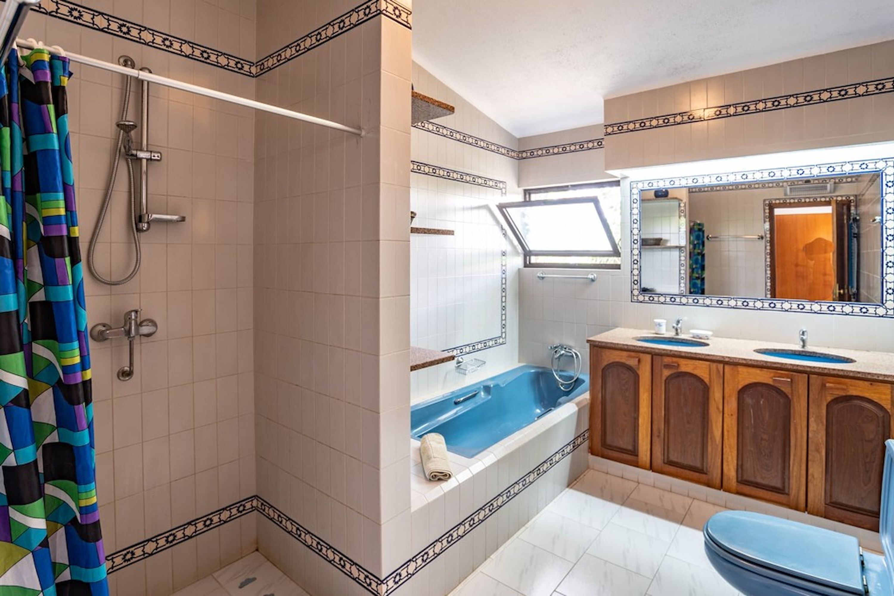 Un baño con ducha, bañera, lavamanos y espejo.