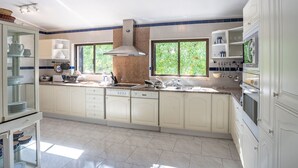 Cocina amplia con alacenas blancas, campana extractora de acero inoxidable y un amplio ventanal que proporciona luz natural.