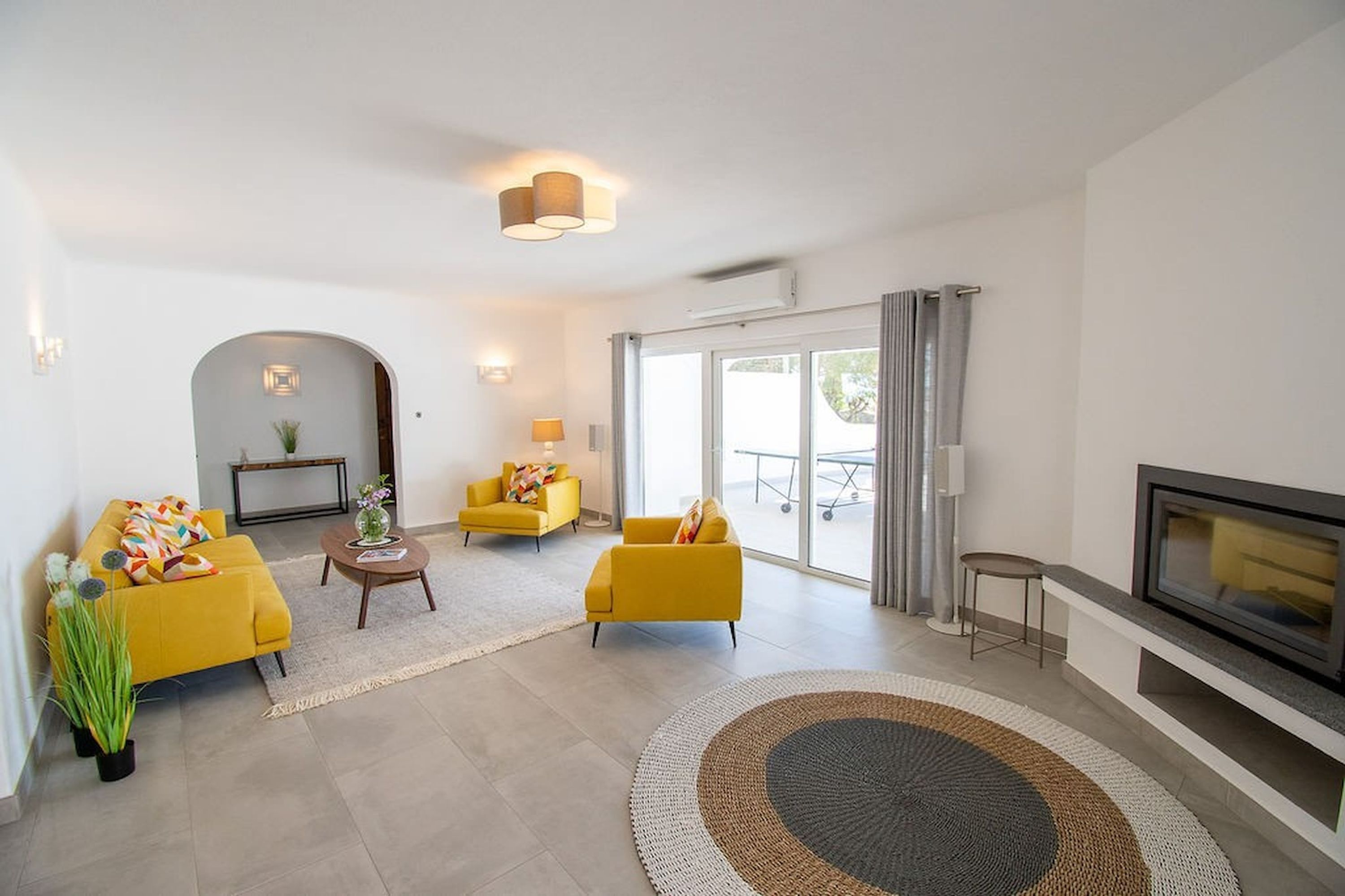 A modern living room with a sofa, armchairs, a coffee table, and a fireplace.