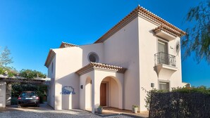 A two-story building with a tiled roof, a balcony, and a paved driveway. - Casa Marta Three Bedroom Villa With sea Views (Lagoa)