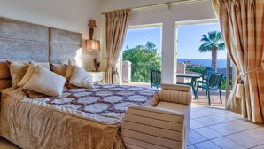A bedroom with a large bed, a nightstand with a lamp, and a view of the balcony with outdoor furniture. - Casa Marta Three Bedroom Villa With sea Views (Lagoa)