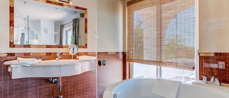 A modern bathroom with a large mirror, two sinks, a bathtub, and a window with blinds.