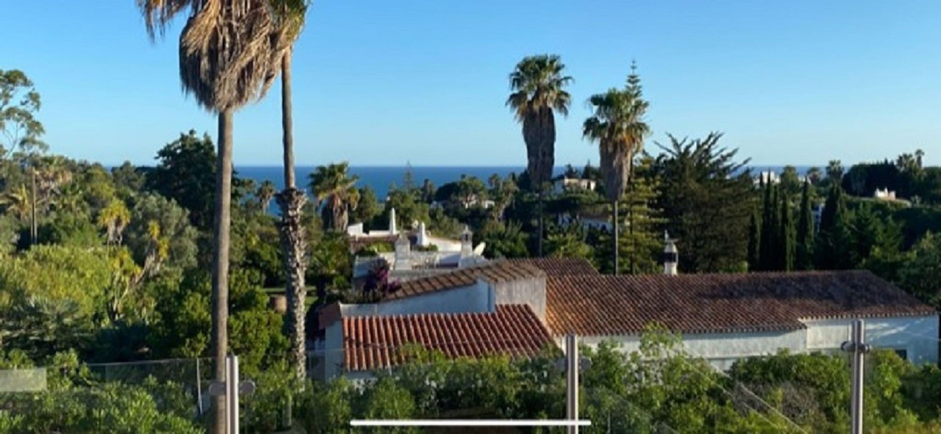 A coastal property with a tiled roof, surrounded by lush greenery and palm trees.