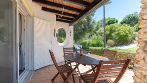 An outdoor patio with a table and chairs, a circular mirror, and a view of greenery. - C22 Quinta do Paraiso Superbly Appointed AND FUR (Lagoa)