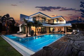 A modern two-story house with a swimming pool, outdoor seating, and a well-lit patio area. - 2 Rua das Palmas Luxurious Stylish and Modern L (Lagoa)