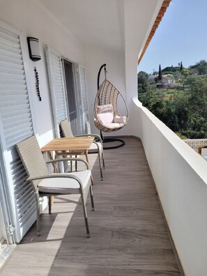 A balcony with a hanging chair, a table, and chairs.