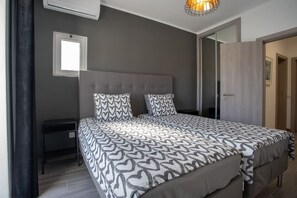 A bedroom with a large bed, a bedside table, a window, and a wardrobe.