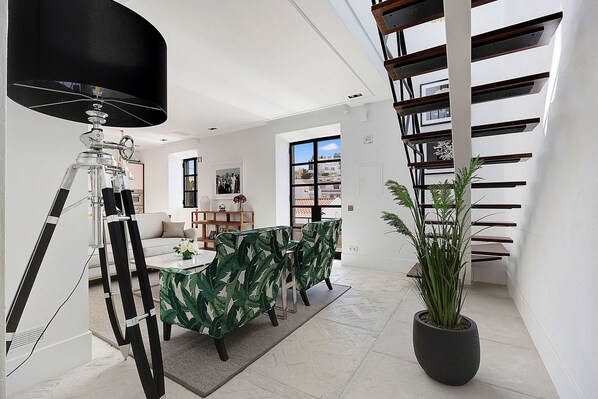 A modern living room with a dining area, a staircase, and a large potted plant. - Queen of the bay in Carvoeiro (Lagoa)