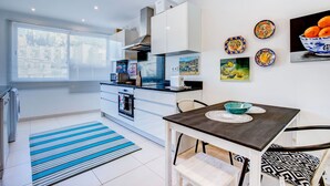 A modern kitchen with white cabinets, a black countertop, and a dining area with a table and chairs. - Jacks Beach House Jack s Beach House Steps From (Lagoa)