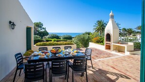 A patio with a table set for breakfast, overlooking a scenic view of the sea and a white building with a tower. - 7 Club Atl Ntico Fabulous Five Bedroom Villa WI (Lagoa)