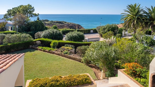 A coastal property with a well-maintained garden, a clear view of the sea, and a stone pathway leading to a building. - 7 Club Atl Ntico Fabulous Five Bedroom Villa WI (Lagoa)