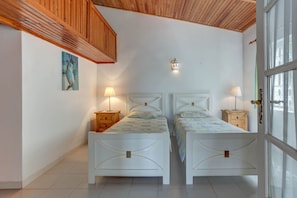 A bedroom with two white beds, wooden headboards, bedside tables with lamps, a painting on the wall, and a window with a view. - Montenegro Superbly Located Family Vila W (Lagoa)