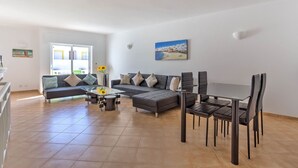 A modern living room with a sofa, coffee table, and dining table with chairs. - Elizabet Modern Apartment in the Heart of the Ci (Lagoa)