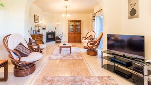 A living room with wicker furniture, a flat-screen TV, and a fireplace. - Engenho Three Bed Villa With Beautiful Countrysi (Lagoa)