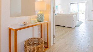 A hallway with a white console table, a lamp, and a wicker basket. - Casa Mel in Carvoeiro (Lagoa)