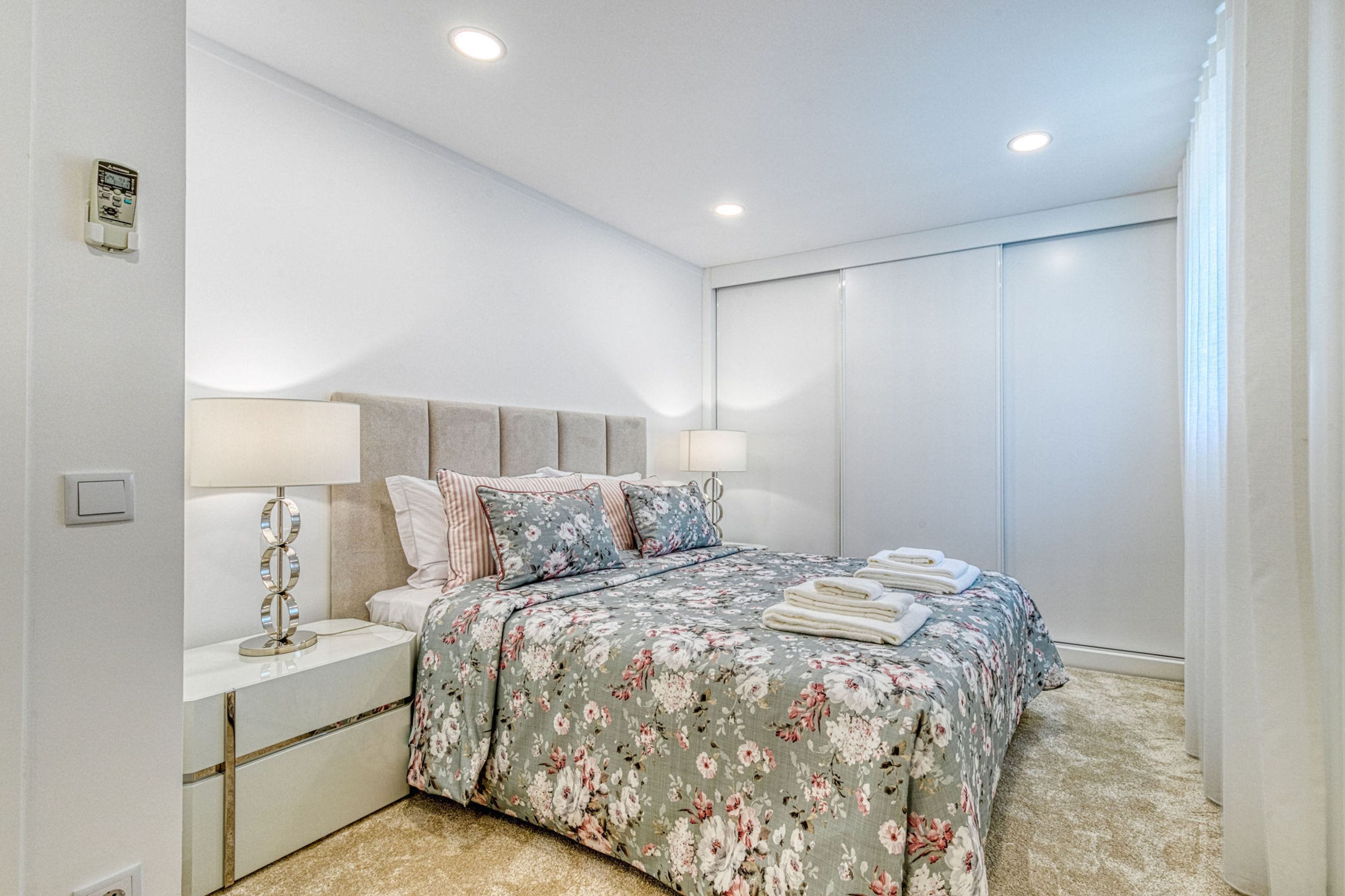 A bedroom with a bed, nightstands, a lamp, and a window with curtains.