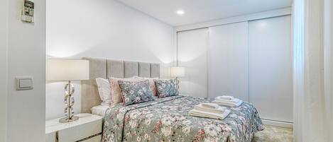 A bedroom with a bed, nightstands, a lamp, and a window with curtains.