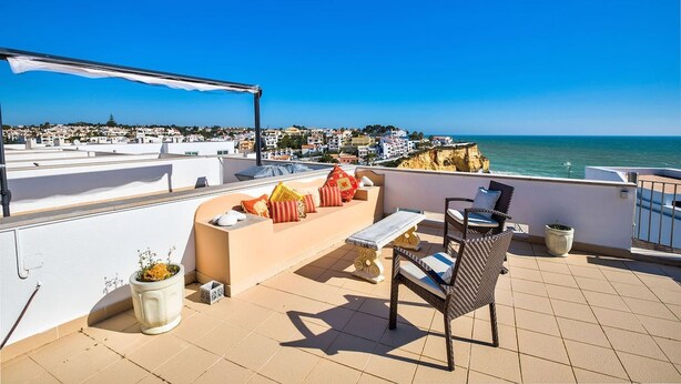 A rooftop terrace with a view of the sea, a seating area with cushions, a table, and a potted plant. - Carvoeiro Bay D Townhouse With Roof Top Jacuzzi (Lagoa)