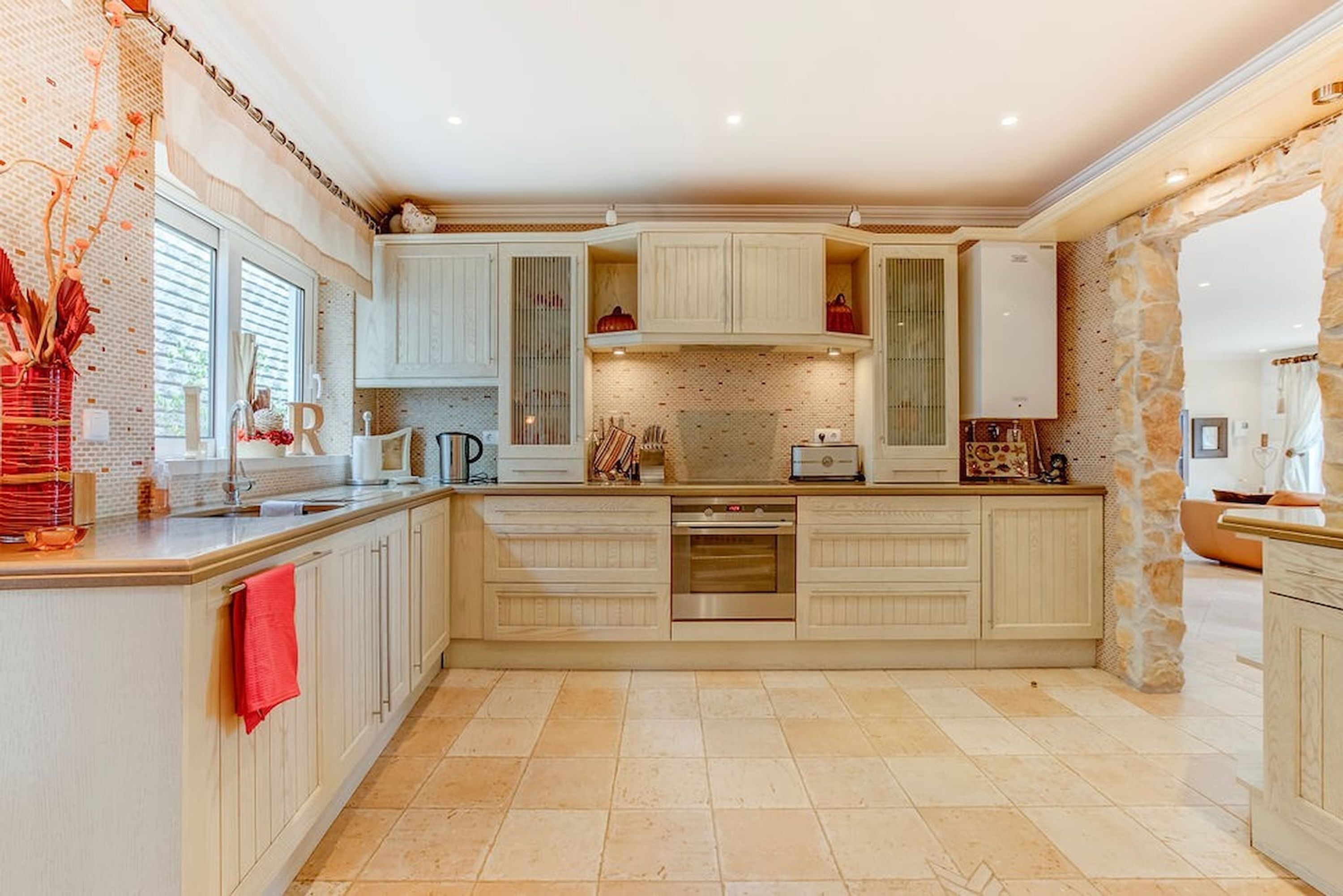 A spacious kitchen with white cabinetry, a large island, and a stone accent wall.