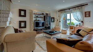 A living room with a TV, sofa, and coffee table. - Carvoeiro Bay D Townhouse With Roof Top Jacuzzi (Lagoa)