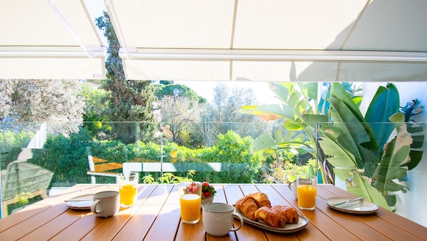 A wooden table with breakfast items including croissants, orange juice, and a coffee cup. - Casa Ella - Beautifully Renovated Townhouse Walkin (Lagoa)