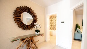 A modern bathroom with a glass console table, a wooden sculpture, and a mirror with a circular frame. - Casa Ella - Beautifully Renovated Townhouse Walkin (Lagoa)