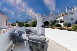Eine Dachterrasse mit Außenbestuhlung und Blick auf weiße Gebäude mit Kuppeln und Türmen.