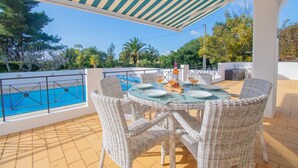 An outdoor dining area with wicker chairs and a table set for two, overlooking a pool and surrounded by greenery. - 61 vdm Superb Villa on Vale do Milho With Heated (Lagoa)