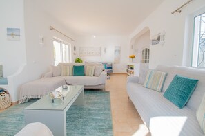 A spacious living area with a sofa, a coffee table, and a dining table.