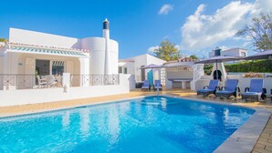 A swimming pool with lounge chairs, a covered seating area, and a white building with a chimney. - 61 vdm Superb Villa on Vale do Milho With Heated (Lagoa)