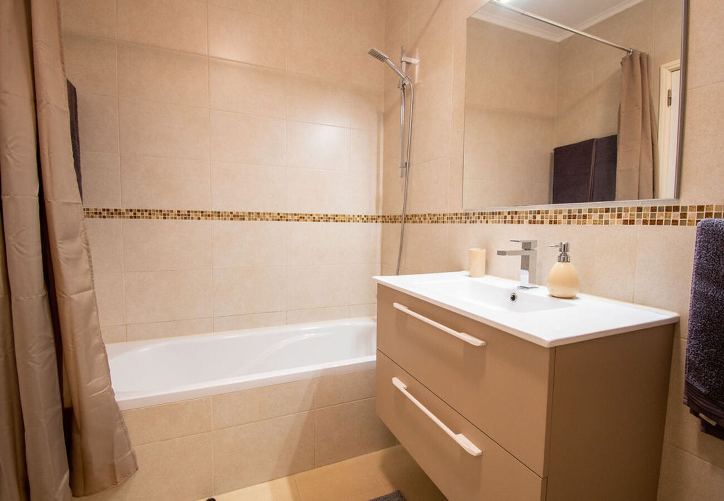 A bathroom with a bathtub, a shower, a sink with a mirror, and a towel rack.