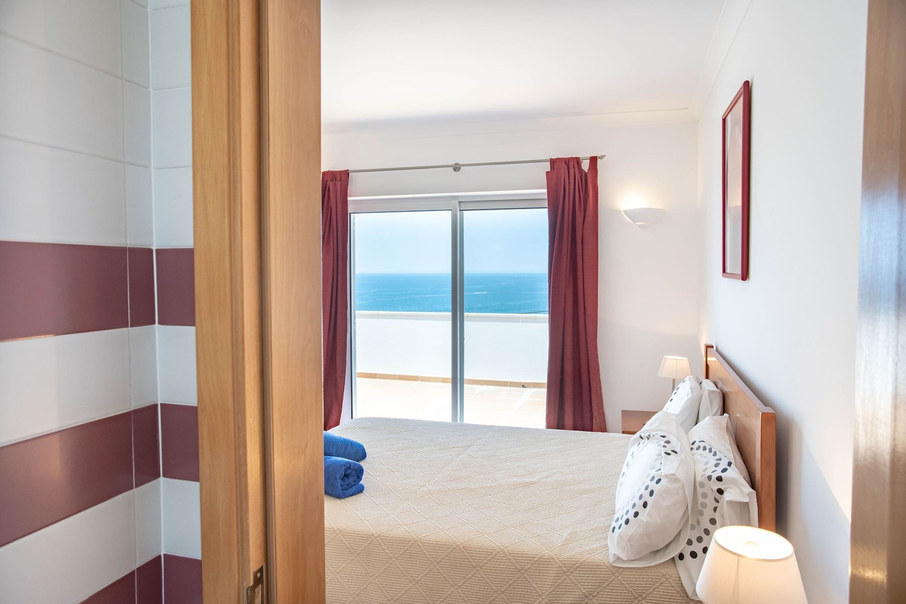 A hotel room with a bed, a view of the sea, and a sliding door.