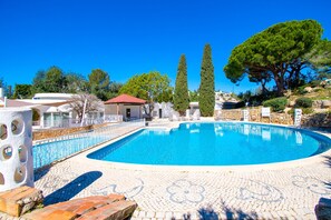 A swimming pool with a tiled deck, surrounded by stone walls and trees. - C65 Quinta do Paraiso (Lagoa)