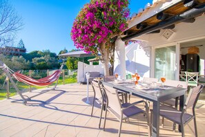 An outdoor patio with a dining table, chairs, and a hammock. - C65 Quinta do Paraiso (Lagoa)