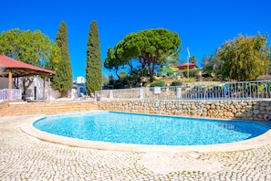 A swimming pool with a stone wall and a gazebo in the background. - C65 Quinta do Paraiso (Lagoa)