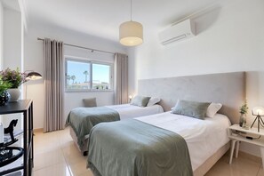 A modern hotel room with two beds, a desk, and a window with curtains. - 7 Boa Nova Immaculately Presented TWO Storey TOW (Lagoa)
