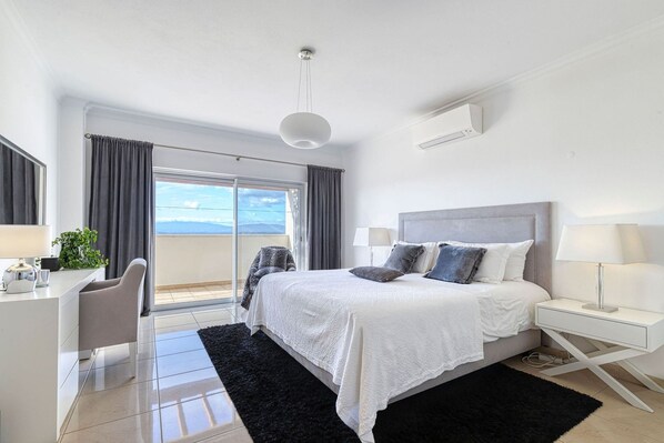 A modern bedroom with a large bed, a desk, and a view of the outdoors. - 7 Boa Nova Immaculately Presented TWO Storey TOW (Lagoa)