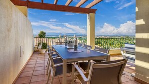 An outdoor patio with a table and chairs, a pergola, and a view of distant buildings and mountains. - 7 Boa Nova Immaculately Presented TWO Storey TOW (Lagoa)