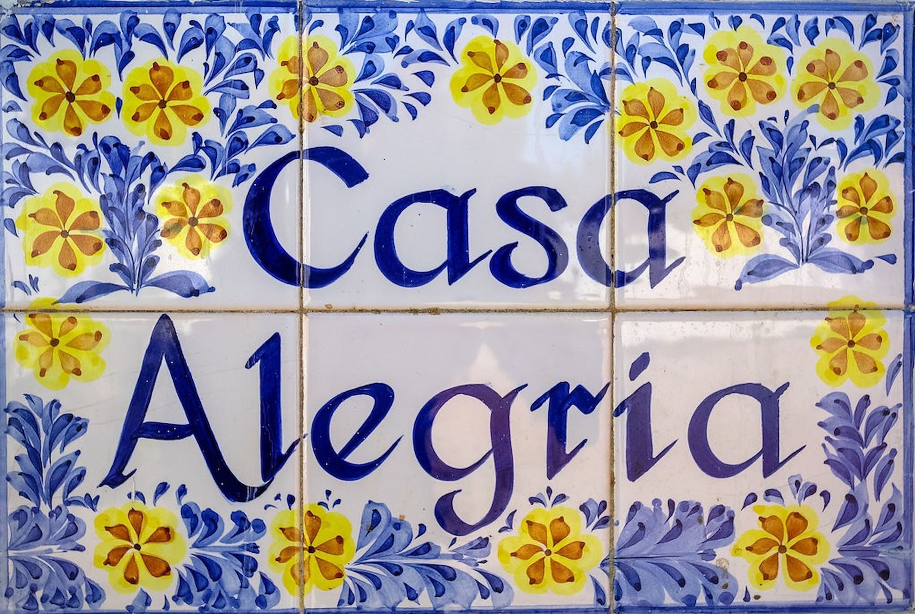 A tile with the text "Casa Alegre" surrounded by floral patterns.