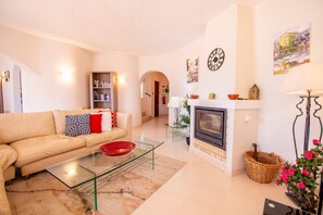 Cozy living room with a sofa, coffee table, fireplace, bookshelf, and a beautiful painting.