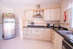 Kitchen features a refrigerator, stove, sink, and ample storage in a well-equipped space.