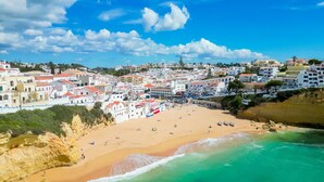 A coastal town with a sandy beach, buildings with red roofs, and a clear blue sky. - Casa Mar a Vista Best View in Town (Lagoa)