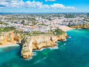 An aerial view of a coastal town with a prominent cliff, a beach, and a densely built residential area. - Casa Mar a Vista Best View in Town (Lagoa)